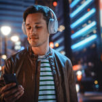 Man walking through city streets listening to an entertainment entrepreneur podcast
