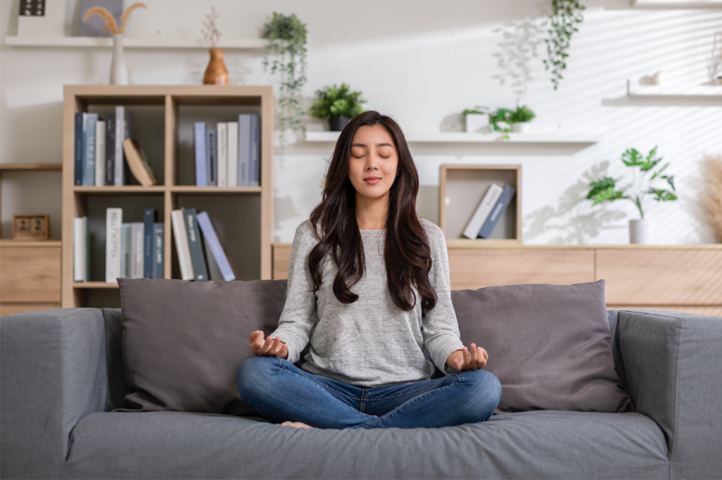 A woman meditates on her couch.